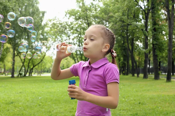 Gadis kecil di taman meniup gelembung — Stok Foto