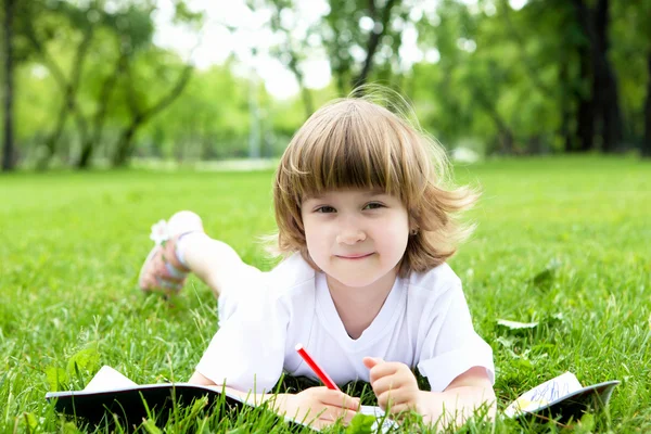 Portrait of little girl reading a book in the park — Stock Photo, Image