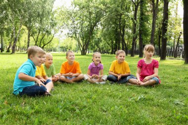 Group of children sitting together in the park clipart