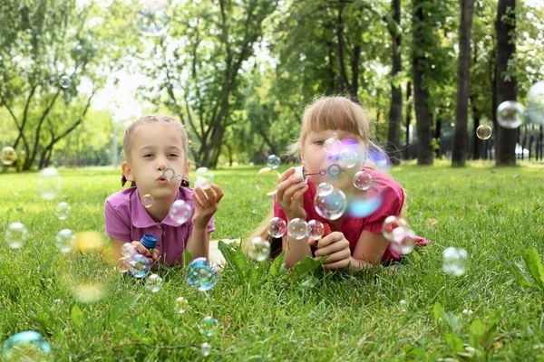 Liten flicka i parken blåser bubblor — Stockfoto
