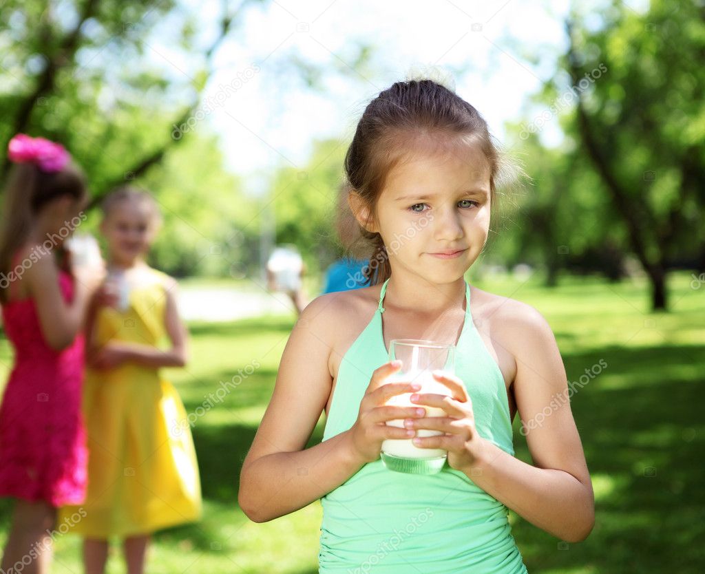 Girl drinking milk in the summer park