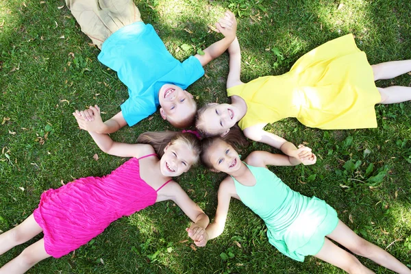 Дети, лежащие на траве в летнем парке — стоковое фото