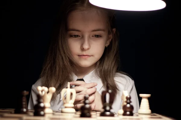 Девушка играет в шахматы под лампой — стоковое фото