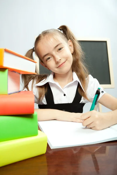 School meisje zit aan de tafel met boeken. — Stockfoto