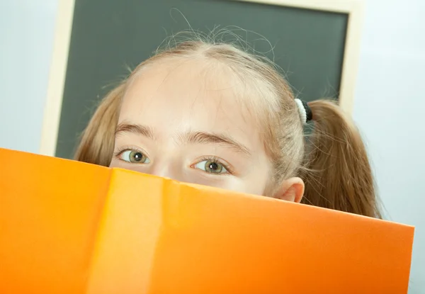 Schülerin versteckt sich hinter gelbem Buch — Stockfoto