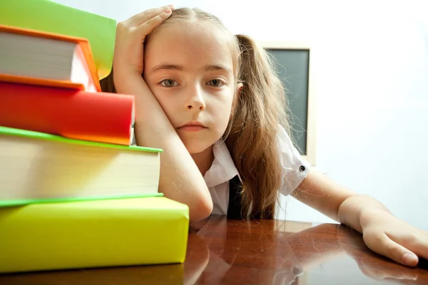 Tired school girl behind stack of books — Stock Photo, Image