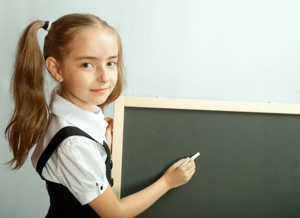 Schoolmeisje bij blank schoolbord. Klaar om te schrijven. — Stockfoto