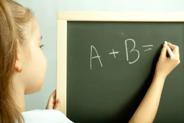 School meisje schrijven oefening op het zwarte bord — Stockfoto
