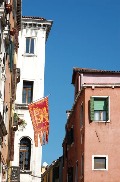 Old houses and symbol of Venice- flag with Saint Mark lion — Stock Photo, Image