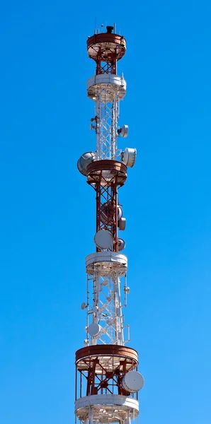 Telekommunikationen står hög med antenner över en blå himmel. — Stockfoto