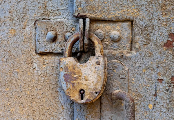 Rezavého visacího zámku na staré kovové dveře — Stock fotografie