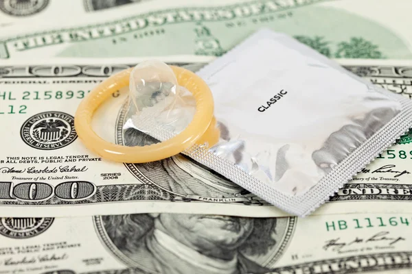 Condoms laying over a pile of us dollars bills — Stock Photo, Image
