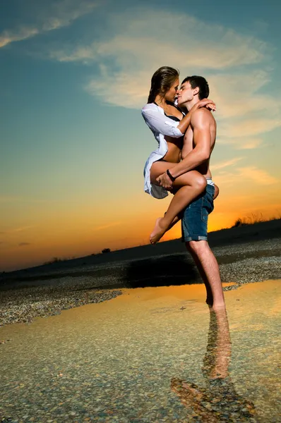 Gün batımında sahilde bir çift. — Stok fotoğraf