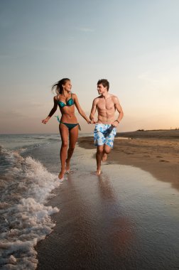 Boy and girl running on beach clipart