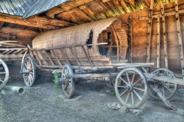 Old wooden coach wheels around a barn. clipart