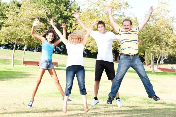 Rodina skákat vysoko ve vzduchu na zelené louce — Stock fotografie