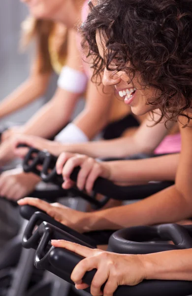 Aantrekkelijke vrouwen over fietsen in een sportschool — Stockfoto