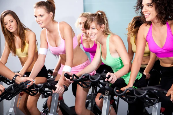 Aantrekkelijke vrouwen over fietsen in een fitnessclub — Stockfoto