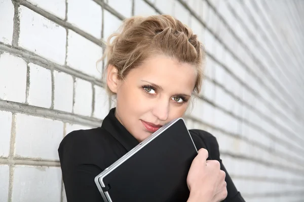 Girl in business suit and with the laptop against wall — Stock Photo, Image