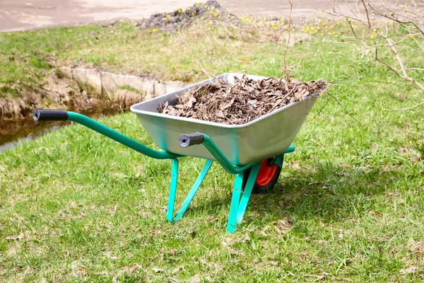 Le chariot de jardin avec tas de feuilles sèches — Photo