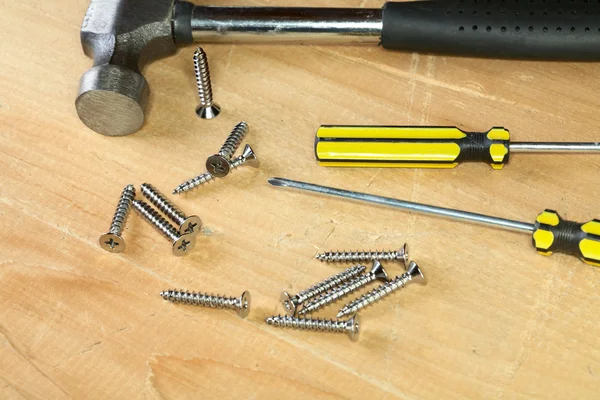Hammer screw-driver screws on a board — Stok fotoğraf