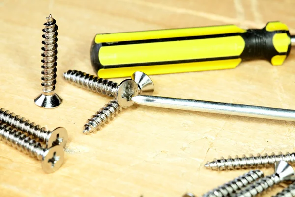 Screw-driver screws on a board — Stok fotoğraf