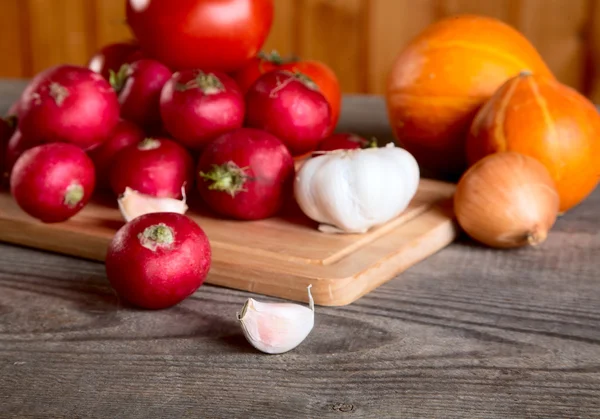 Onions garlic garden radish on a table from boards — Stock Photo, Image