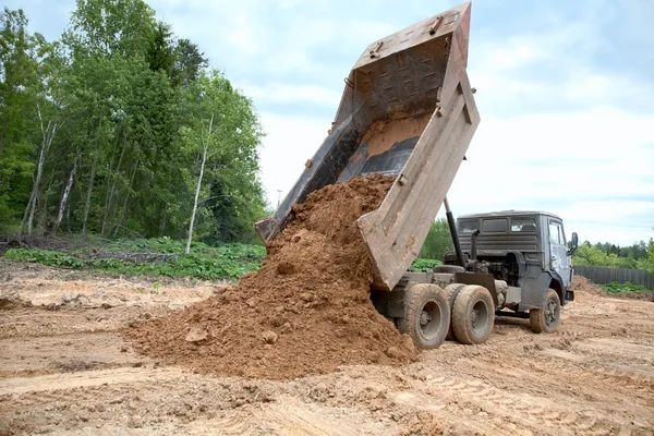 Dump-lichaam vrachtwagen verwijderd een grond Stockafbeelding