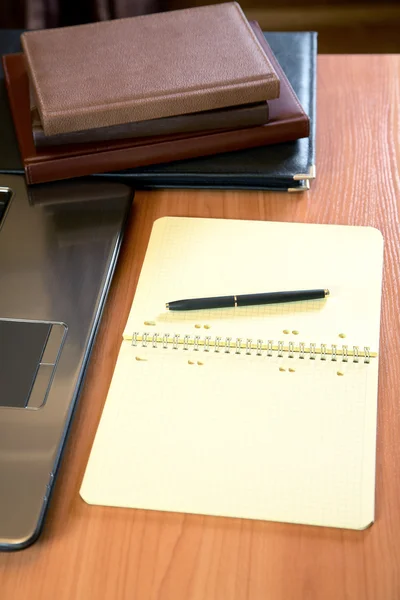 Pile of organizers the laptop and pen on a desk — Stock Photo, Image