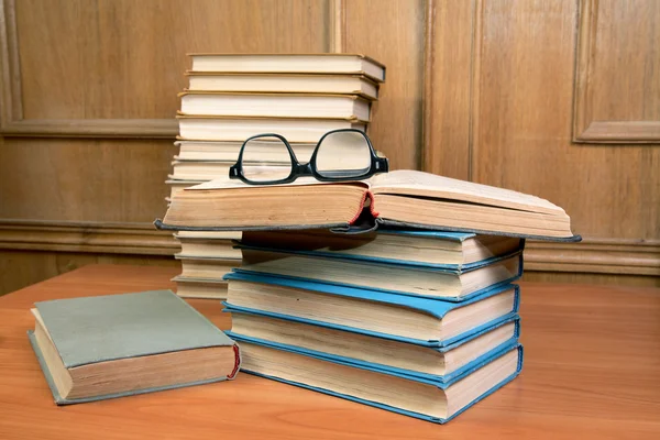 Högen av böcker och gamla glasögon på ett bord — Stockfoto