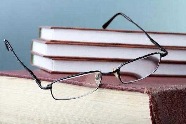 Glasses hang down from a pile of books — Stock Photo, Image
