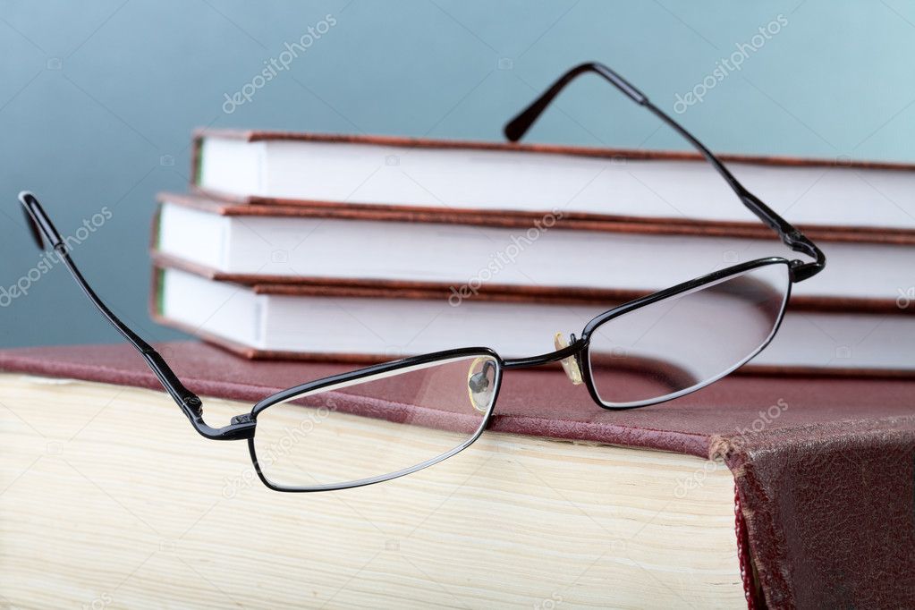 Glasses hang down from a pile of books