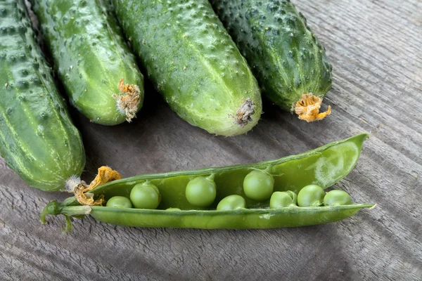 stock image Green cucumbers and peas pod on a table