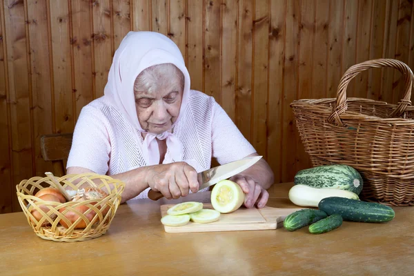 De oude vrouw snijdt plantaardige beenmerg — Stockfoto