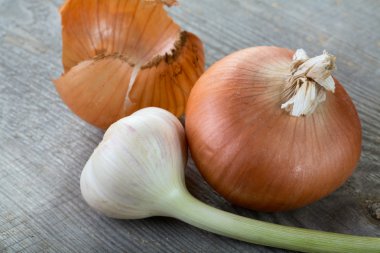 Garlic and onions with peel on a table clipart