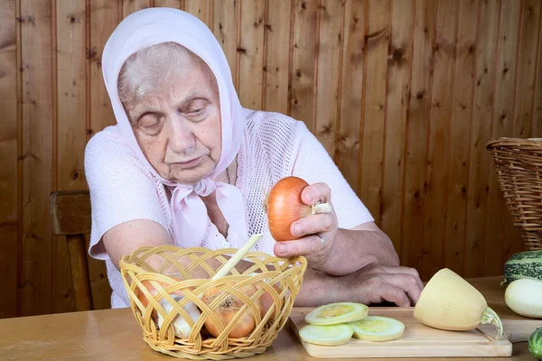 De oude vrouw houd uien — Stockfoto