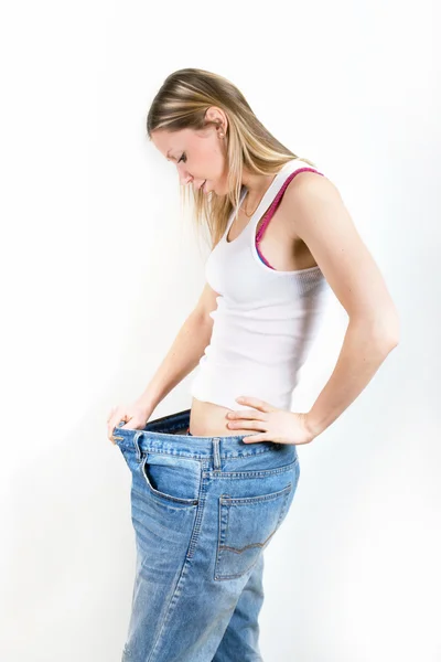 Mutlu genç kadın kilo kaybettikten sonra eski kot pantolon — Stok fotoğraf