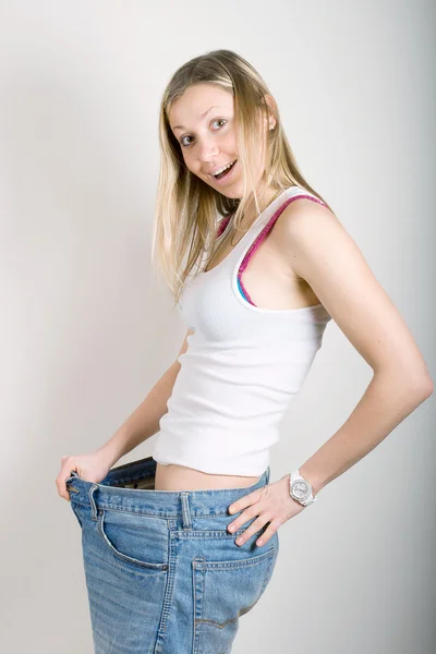 Счастливая молодая женщина в старых джинсах брюки после потери веса — стоковое фото