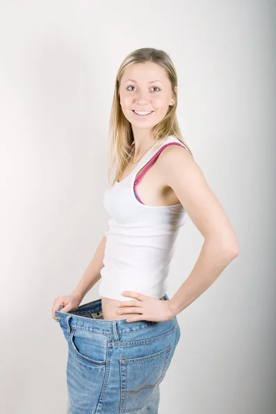 Happy young woman in old jeans pant after losing weight — Stock Photo, Image