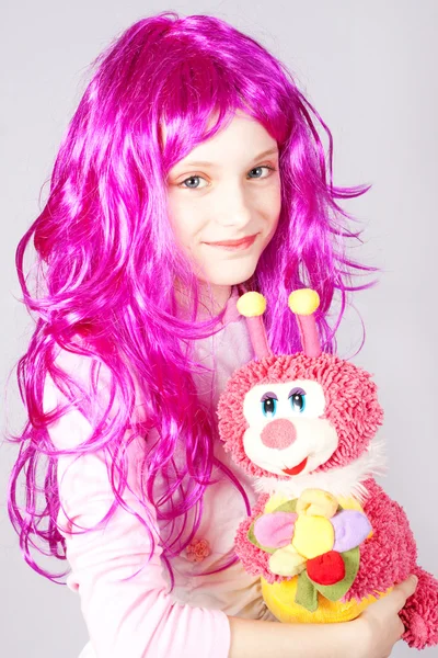 Menina em uma peruca com uma lagarta de brinquedo — Fotografia de Stock