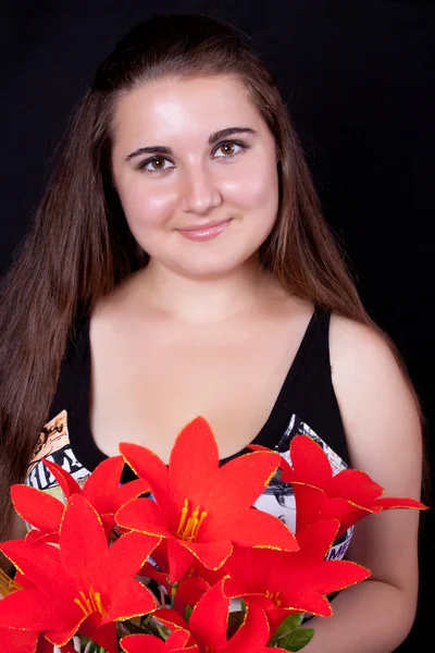 Красива дівчина з довгим волоссям і букетом червоних квітів — стокове фото