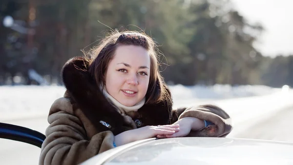 Женщина возле своей машины на зимней дороге — стоковое фото
