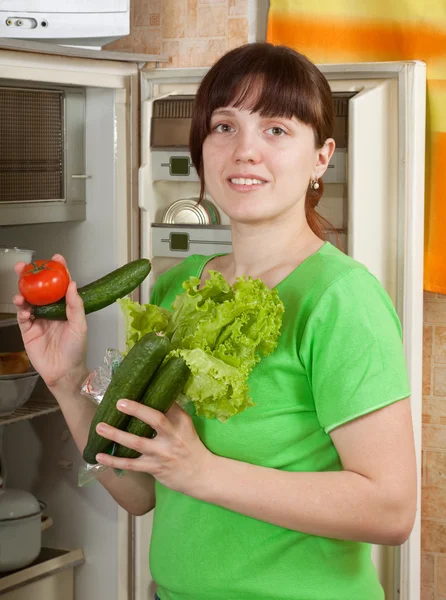 Женщина кладет свежие овощи в холодильник — стоковое фото