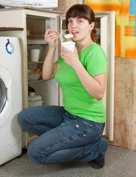 Vrouw eten yoghurt uit koelkast — Stockfoto