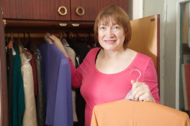 Mature woman looking at clothes clipart