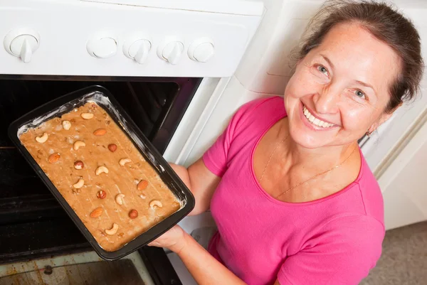 Женщина кладет тесто в духовку — стоковое фото