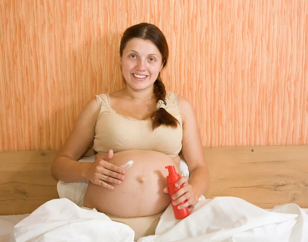 Mujer embarazada frota crema — Foto de Stock