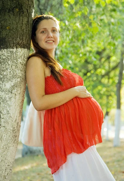 Беременная женщина на летней аллее — стоковое фото