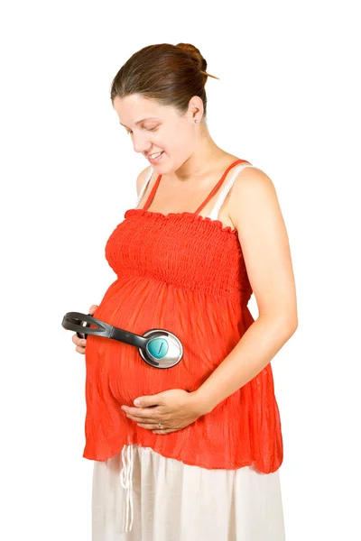 Беременная женщина с наушниками на животе — стоковое фото