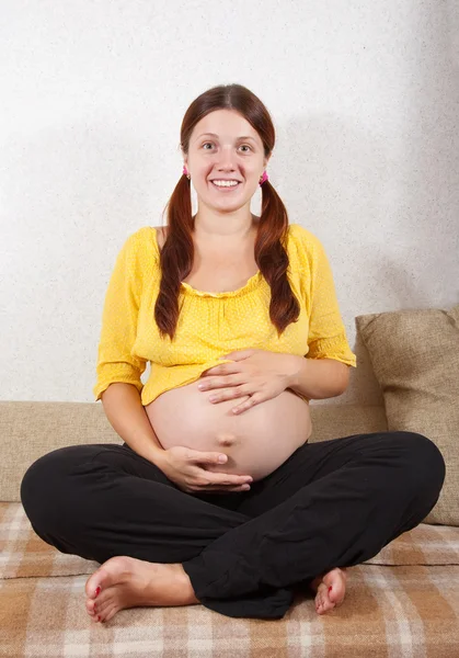 妊娠中の女性はソファに座って — ストック写真